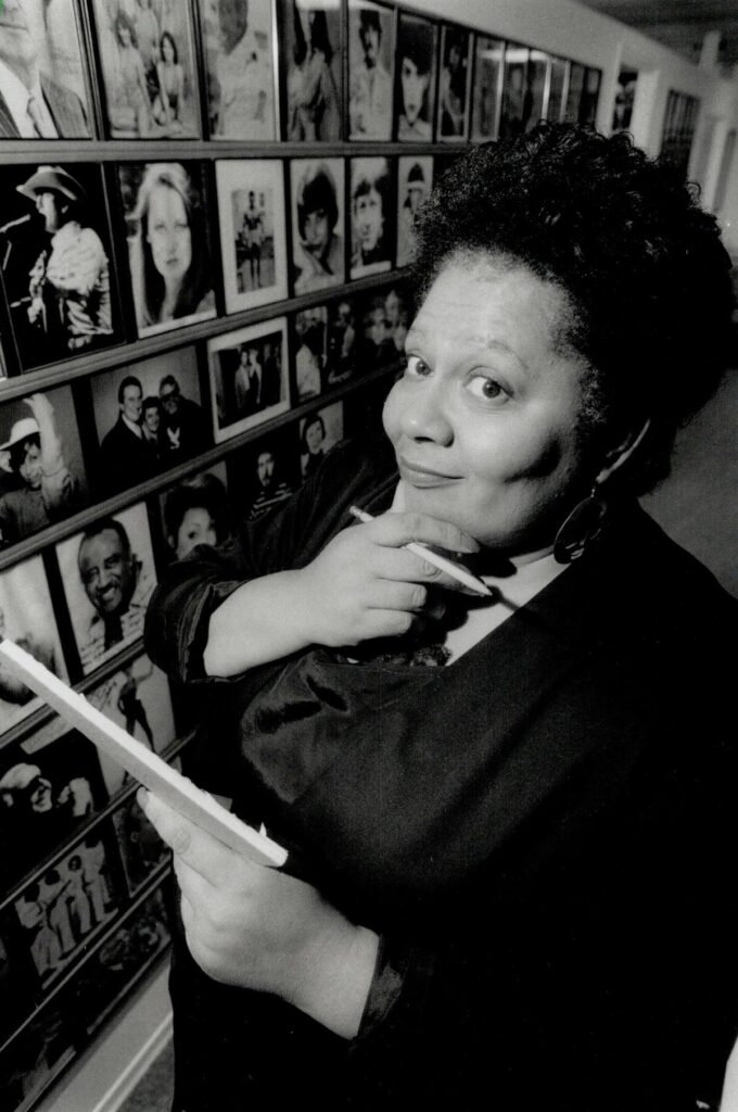 Jackie Richardson holding a pen and rubbing her chin with the same hand, while holding foam core and looking at the camera with a sense of intrigue.