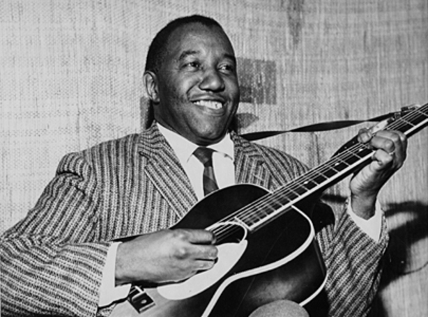 Jackie Washington playing the guitar with a joyful expression.