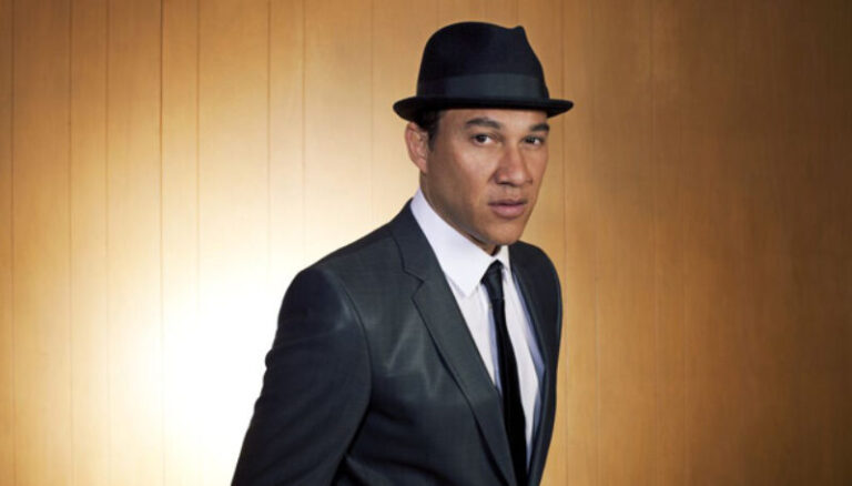 Jarvis Church posing for shoot in a sleek suit and a fedora.