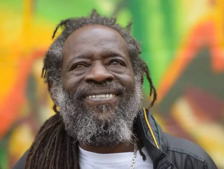 Bernie Pitters standing in front of Reggae Lane mural, blurred background