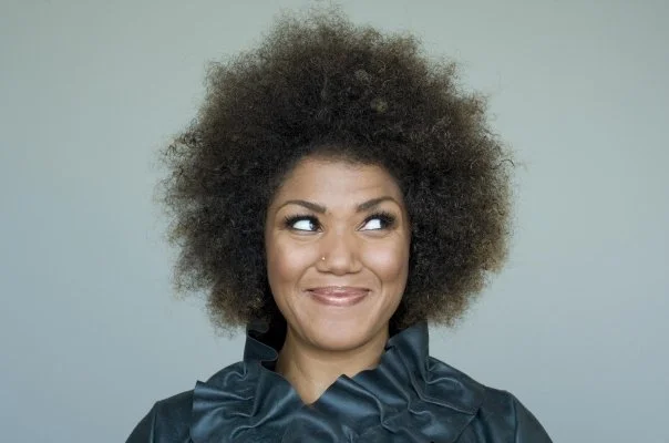 Measha Brueggergosman smiling mischievously as her eyes glance to the side for a headshot.