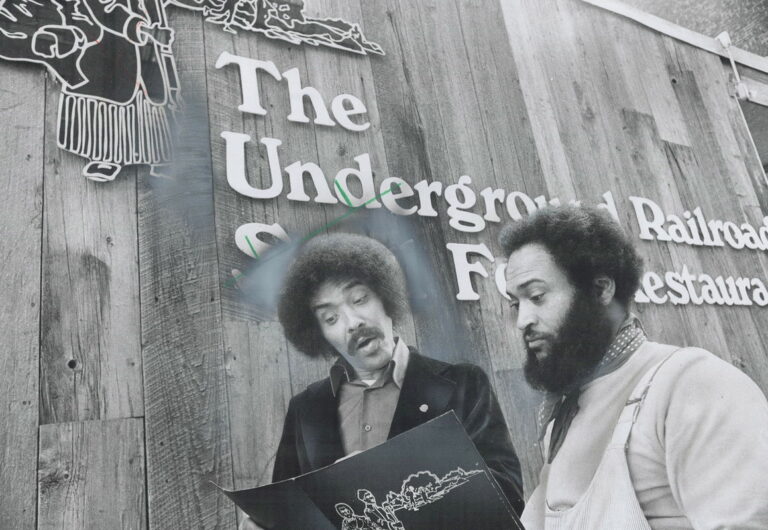 black and white photograph of two people reading something in front of "The Underground Railroad Soul Food Resturant"