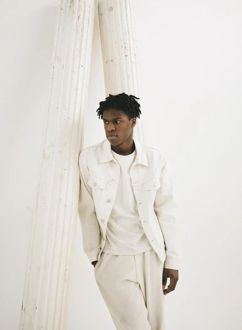 Daniel Caesar, leaning against a pillar.