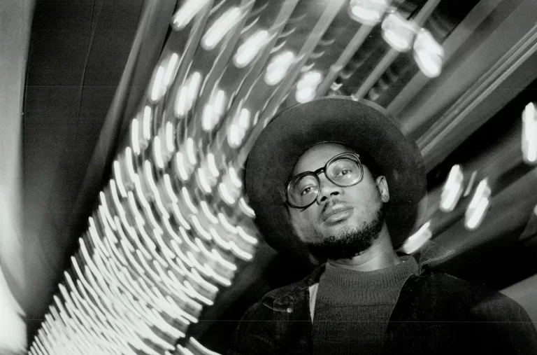 Clifton Joseph in glasses and hat, black and white, blurred lights in background