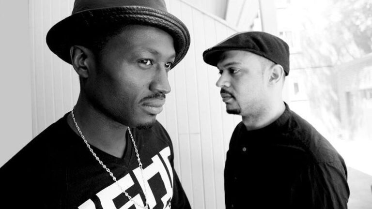 Black and white photo of two men wearing hats facing each other