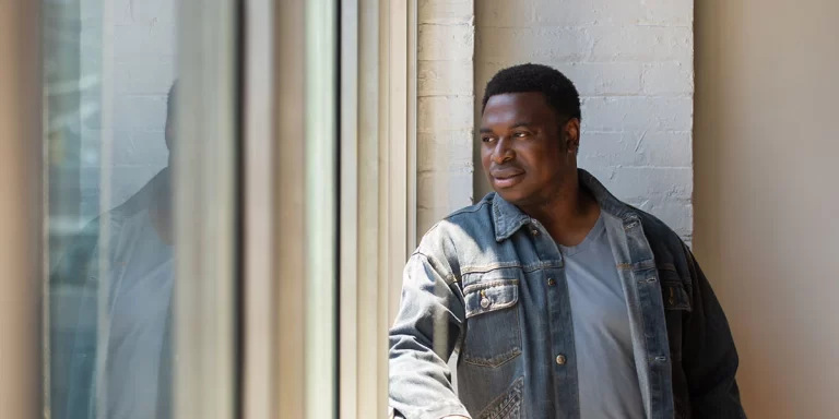 Thompson Egbo-Egbo looking out of window and wearing jean jacket