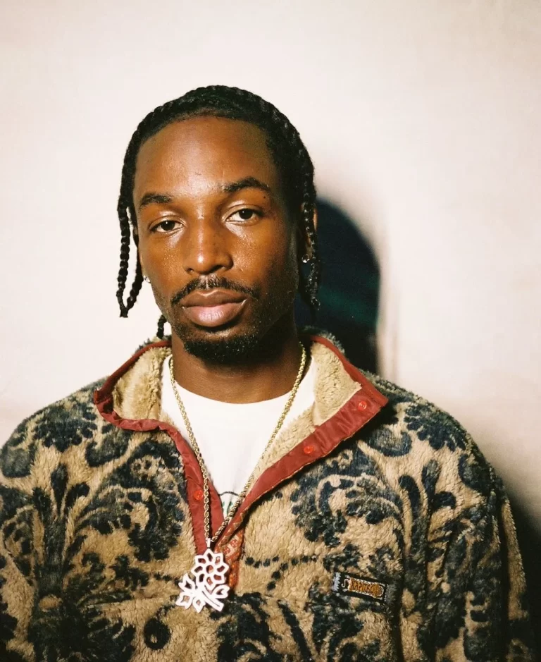 Jazz Cartier in plush jacket, looking into camera