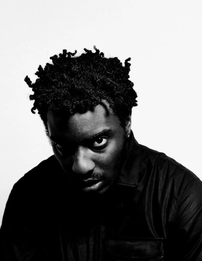 A black and white photograph of Sean Leon with his his head slightly tilted downwards, in front of a white background