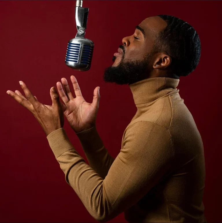 Gary Beals singing into mic, red background