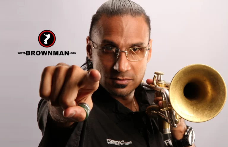 Brownman playing trumpet in front of graffiti background