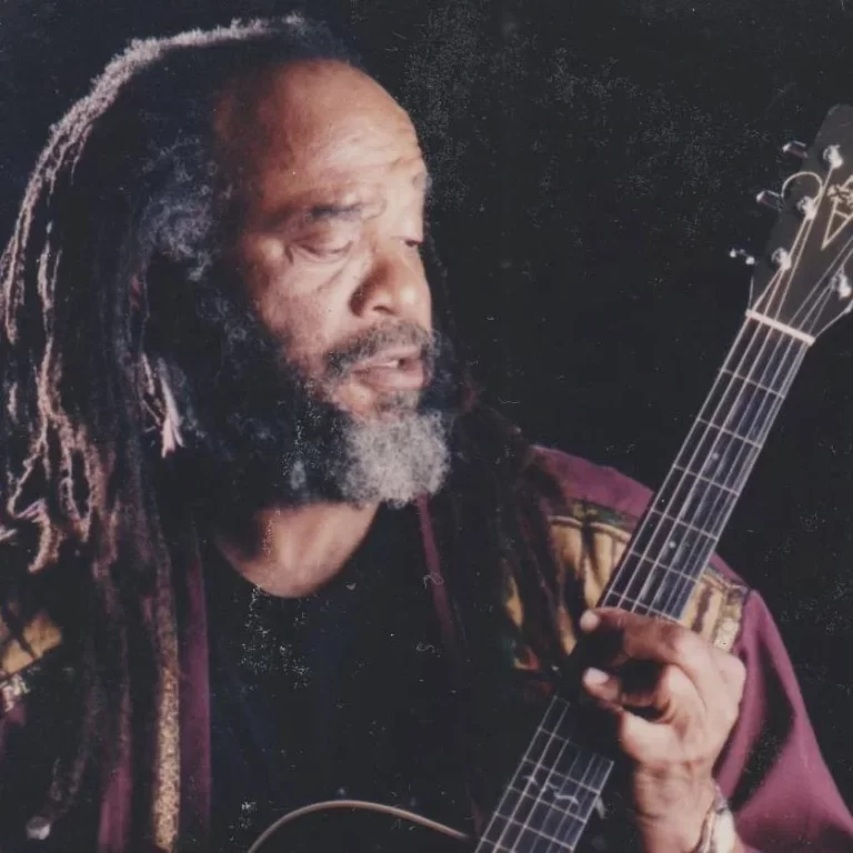 Close-up of Ernie Smith playing guitar, black background