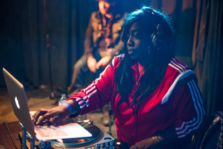 Dj Mel Boogie DJing on stage with a turn table and laptop in front of her