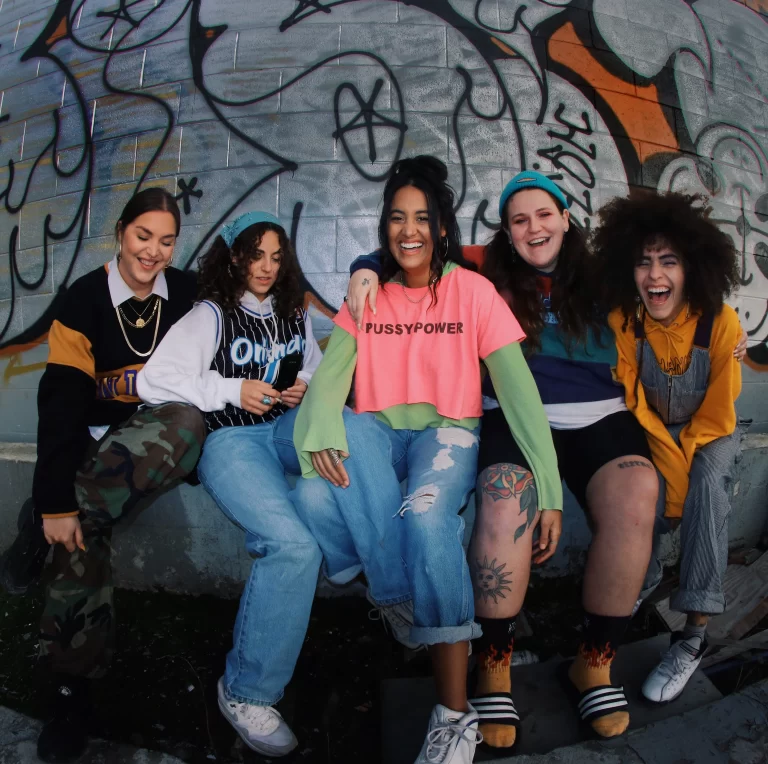 Naduh sitting together as a group in front of a graffiti wall