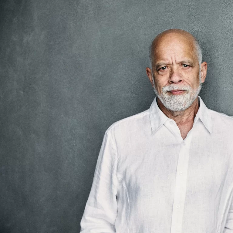 Dan Hill posing off side in front of grey background, wearing white button up