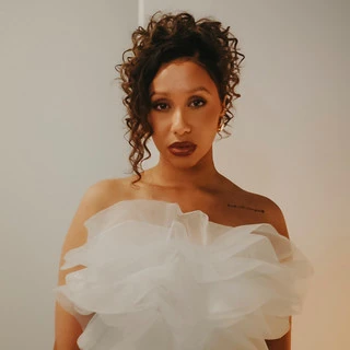 Justine Tyrell looking into camera wearing white mesh dress, white background