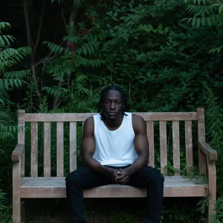 TOVA posing on bench in front of forest
