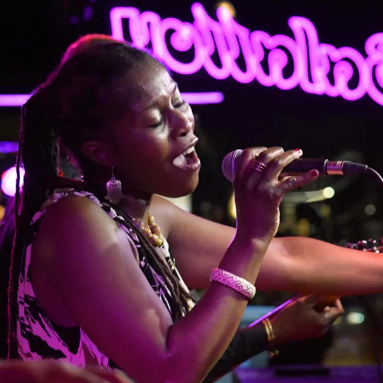 Juliet Nelson singing on stage in front of neon sign