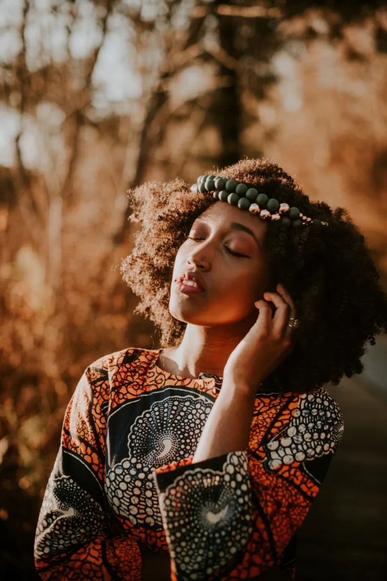 A posed shot of Yvonne Kushe with her eyes closed, hands near face, outside