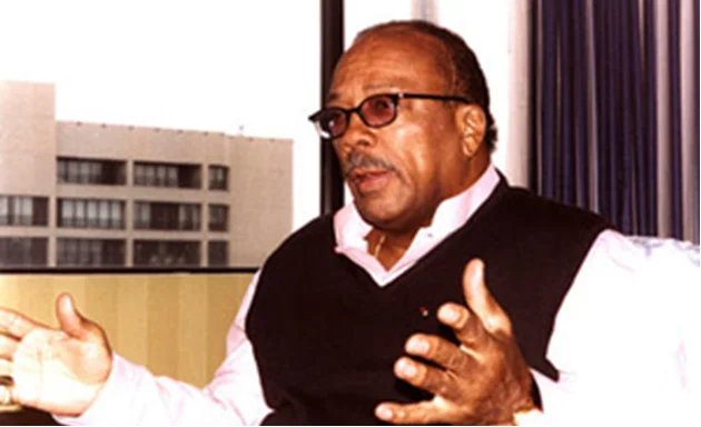 Medium shot of Quincy Jones sitting while talking with hands spread